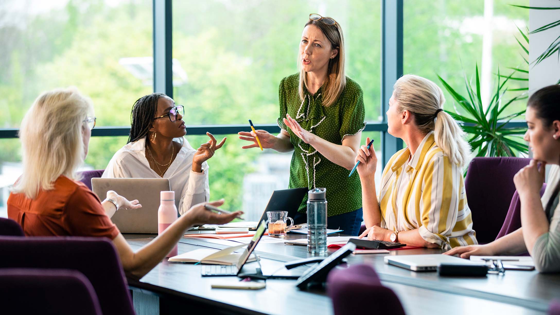 A woman explaining in front of other women employees in a meeting room. 