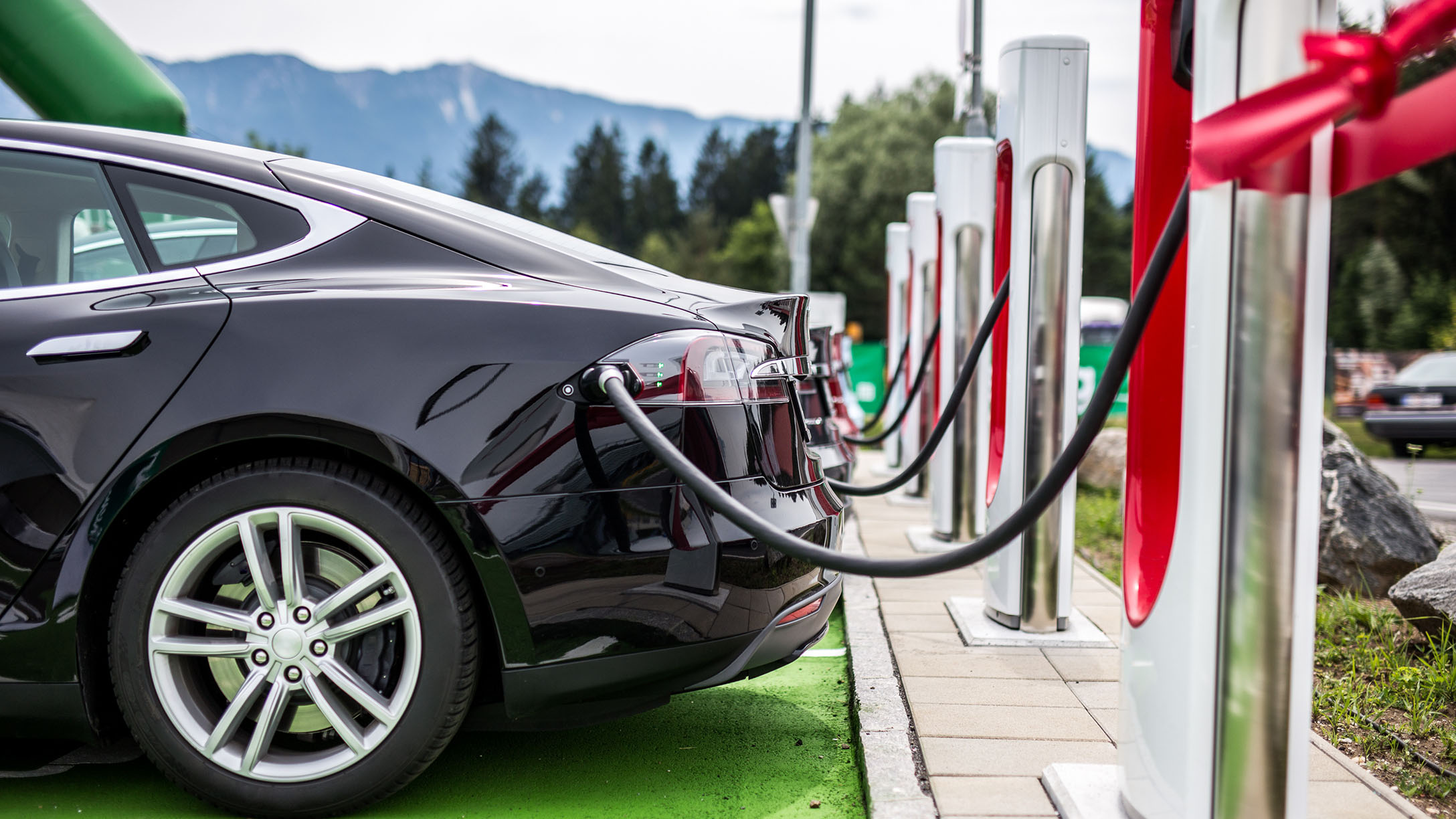 An electric car standing in charging station getting charged.