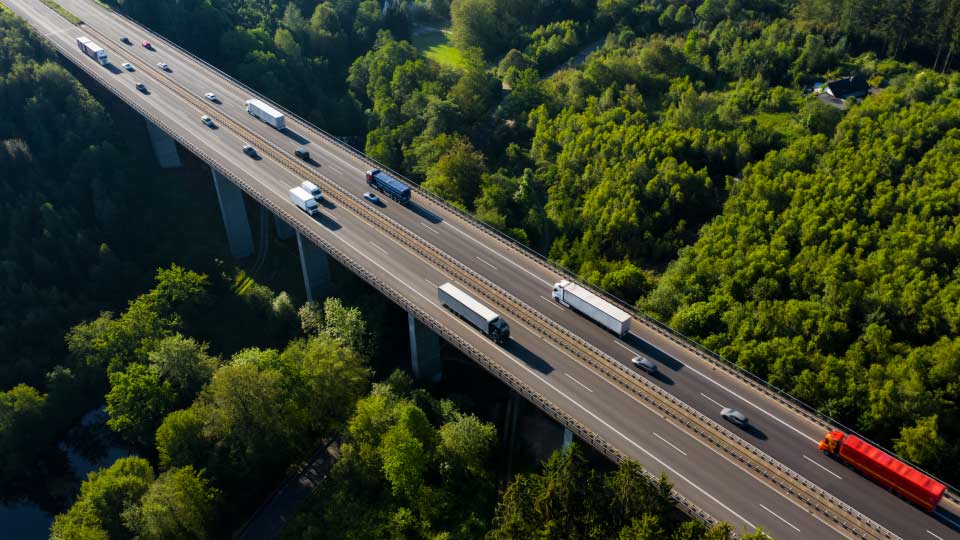 snelweg met rijdend vrachtverkeer en groene bomen