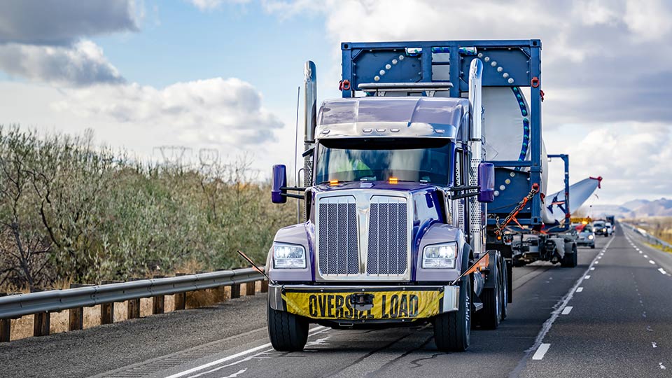 blue truck carrying oversize load on the road