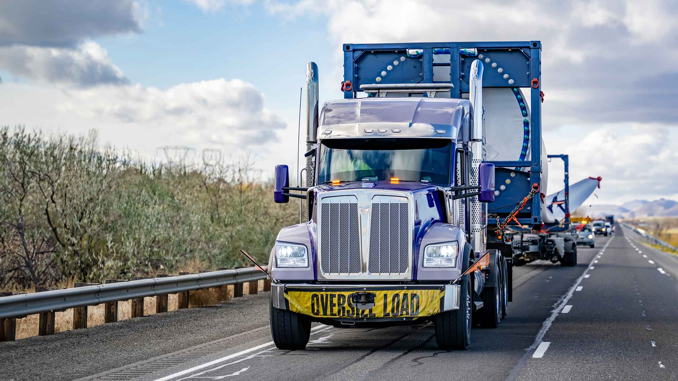 blue truck carrying oversize load on the road