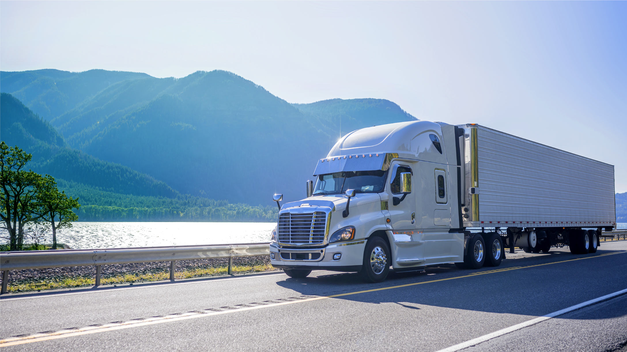 Truck driving down highway with mountains in the background