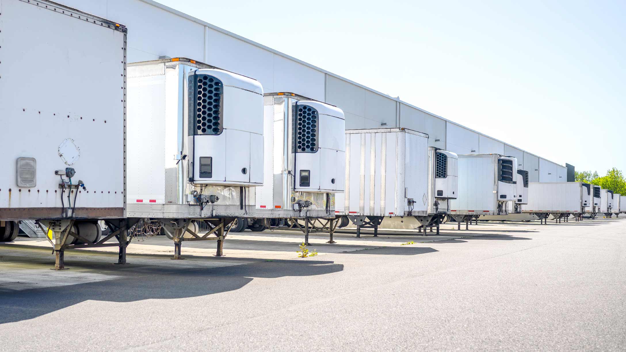 Multiple hgv trailers parked in a row at the back of a warehouse