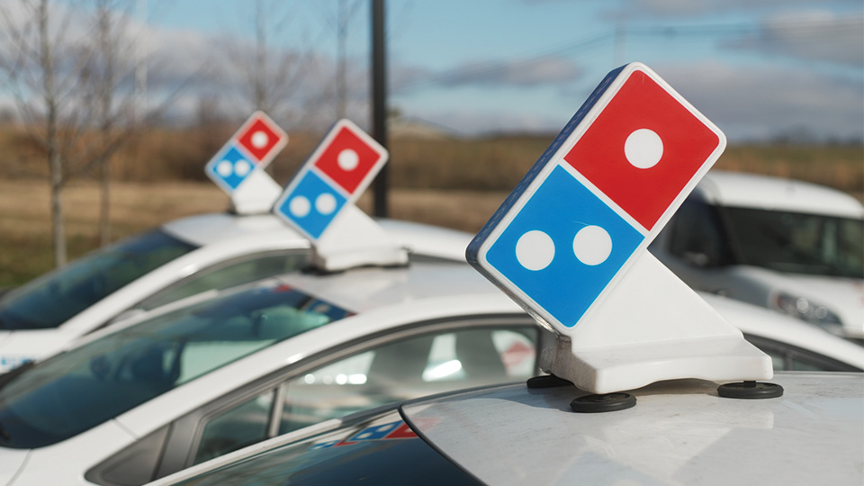 three dominos delivery cars parked next to each other