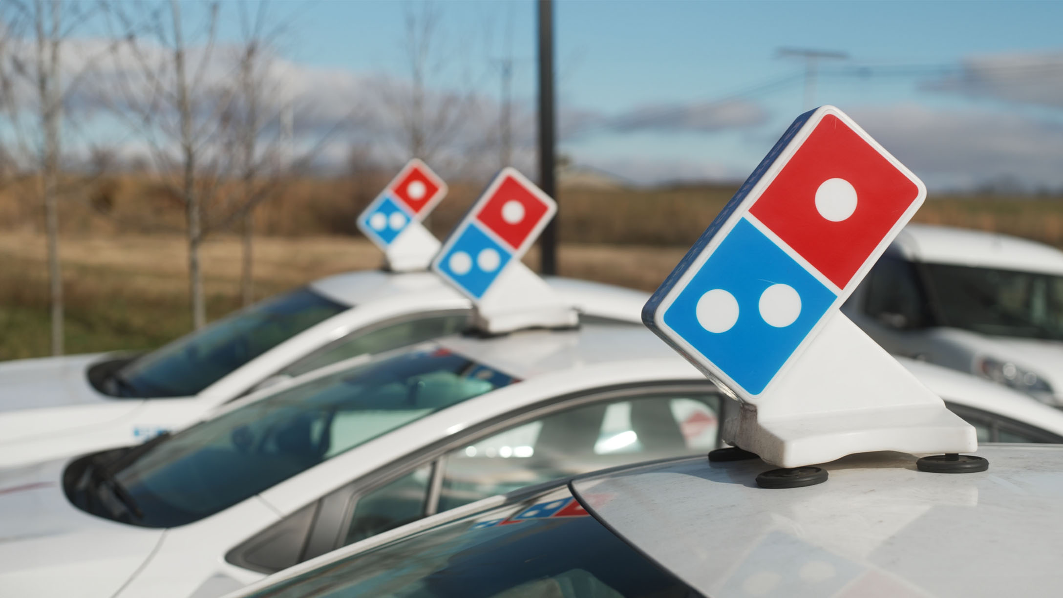 three dominos delivery cars parked next to each other