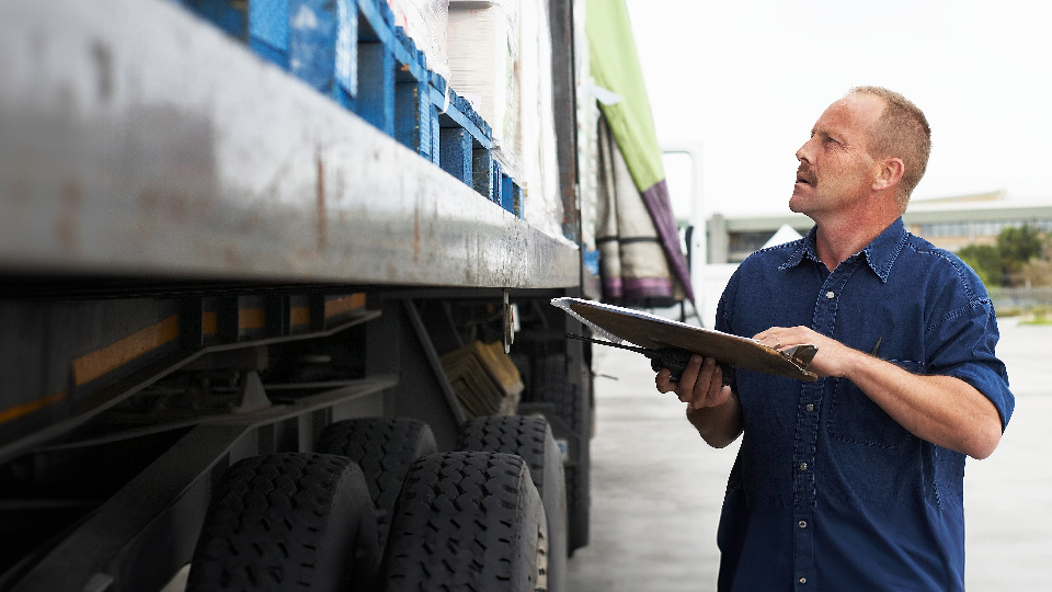 Person standing outside a truck doing holding a tablet