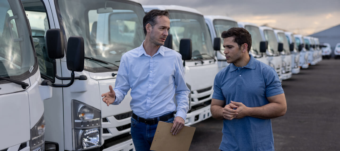 Two men walking alongside a row of fleet cars talking. 