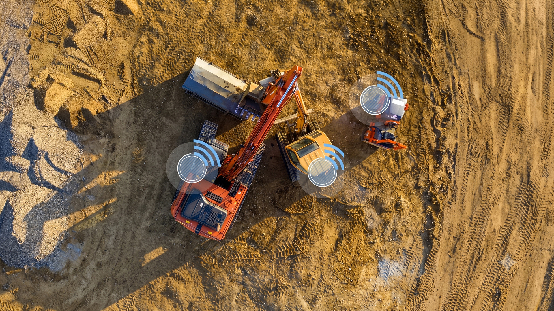 Aerial view of connected construction equipment on a worksite with wireless signal icons representing asset tracking