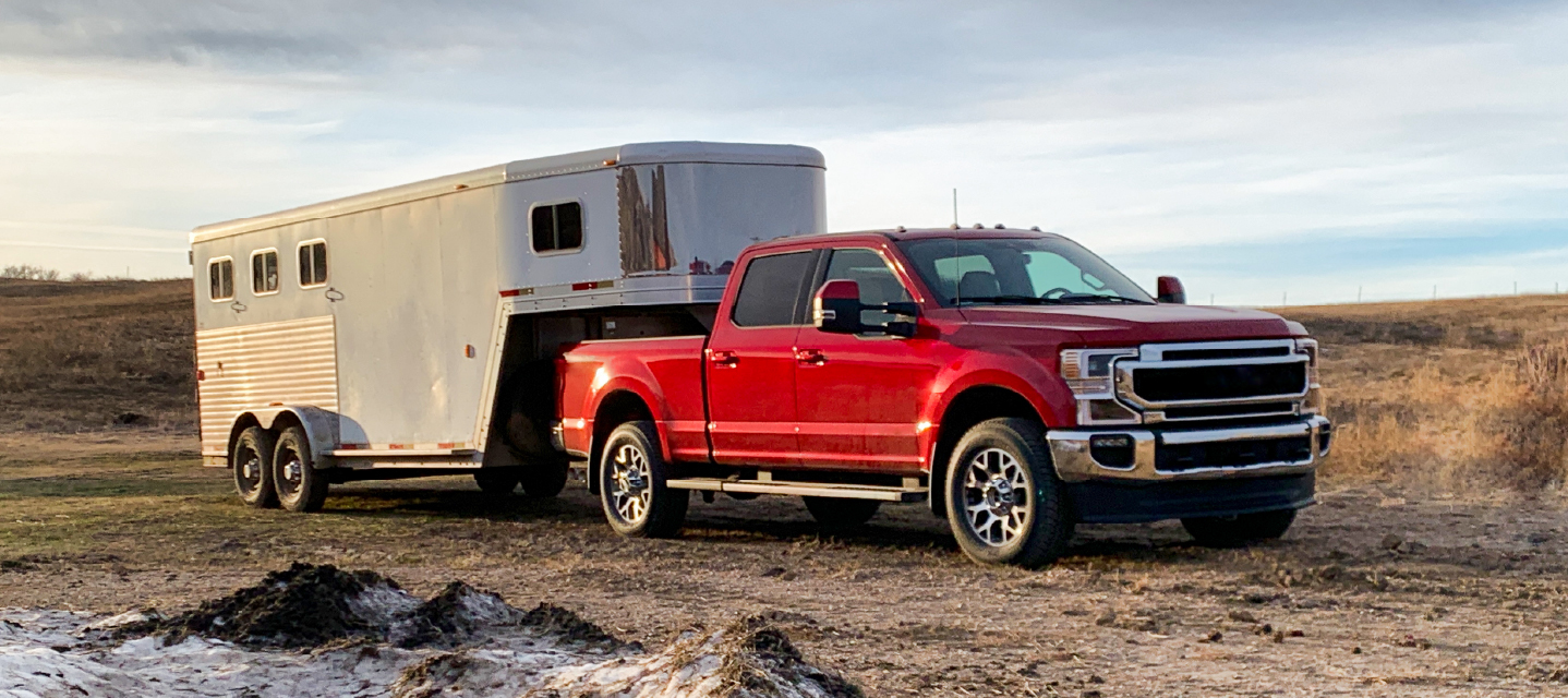 a photo of a red truck carrying a trailer.