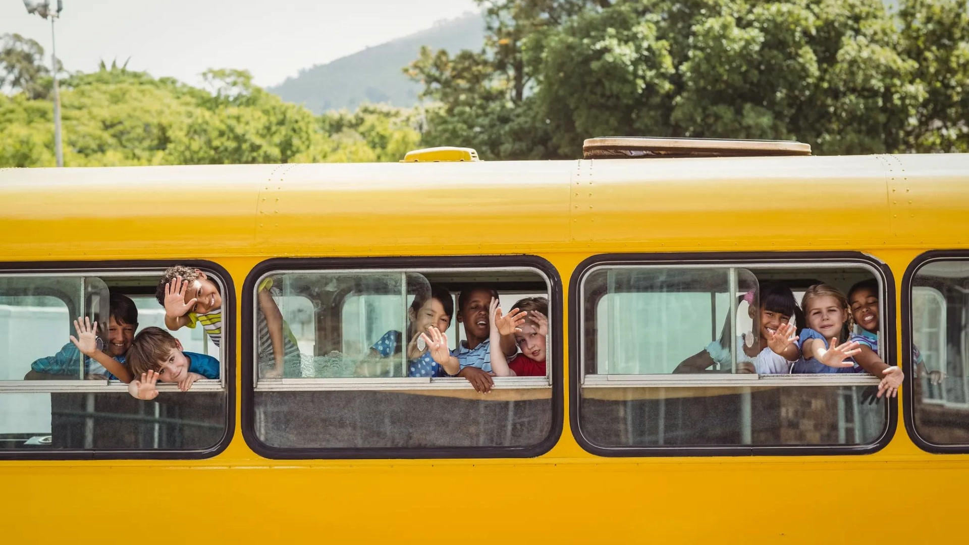 students waving from inside a school bus