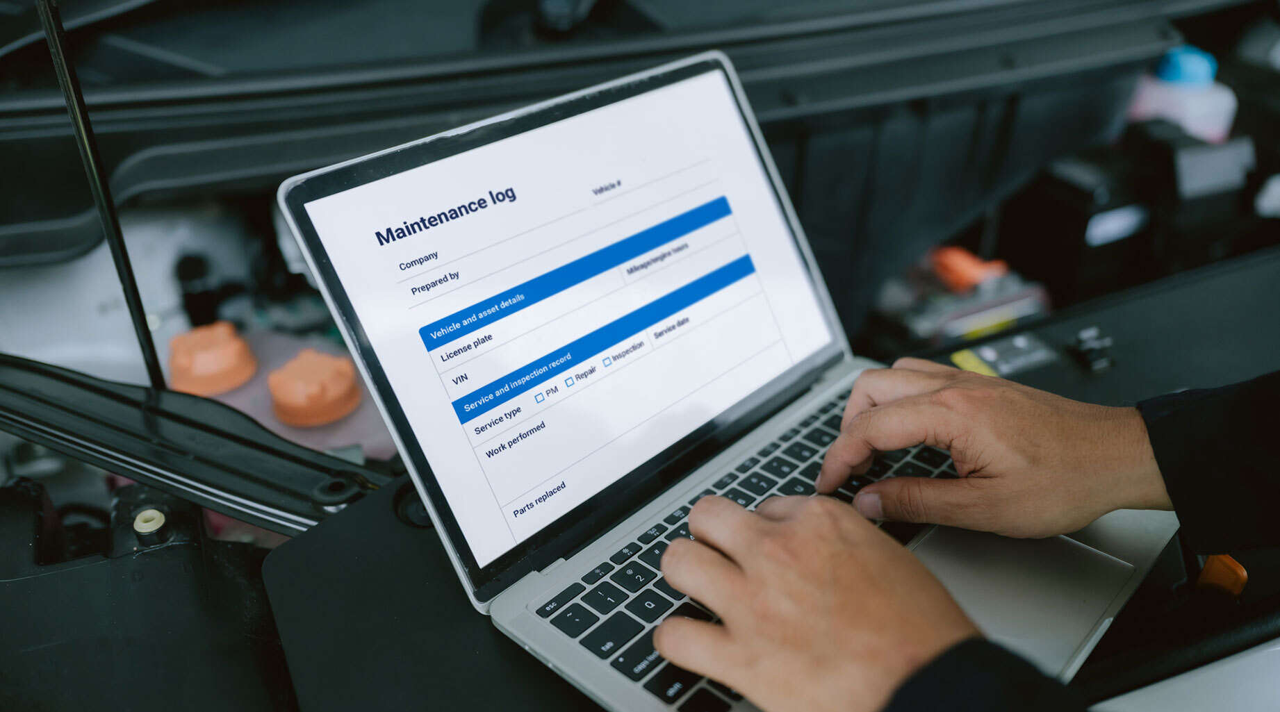 Person’s hands on a keyboard with a maintenance log PDF template displayed on the screen
