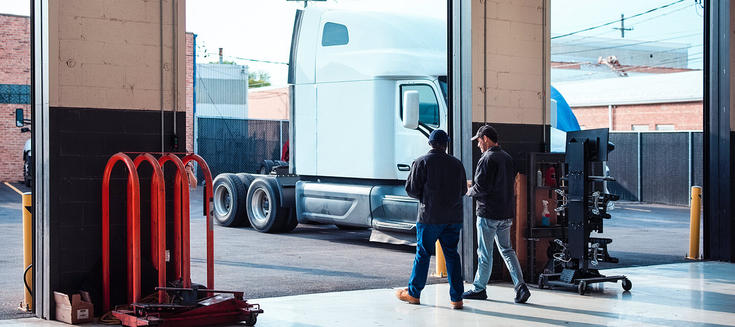 Two men walking through a fleet maintenance garage.