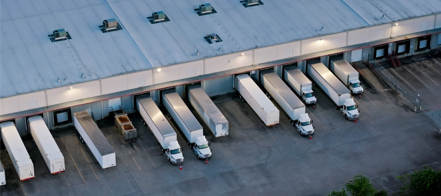 A fleet center with a row of white trucks parked outside.
