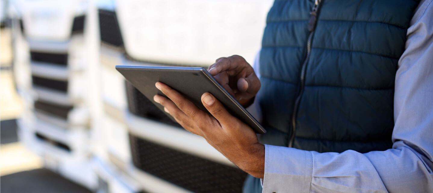 a person holding an ipad standing in front of fleet vehicles. 