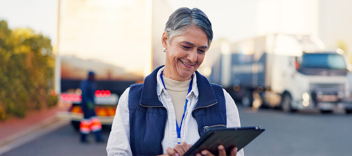 photo of a fleet manager using a tablet to monitor a group of commercial vans or trucks