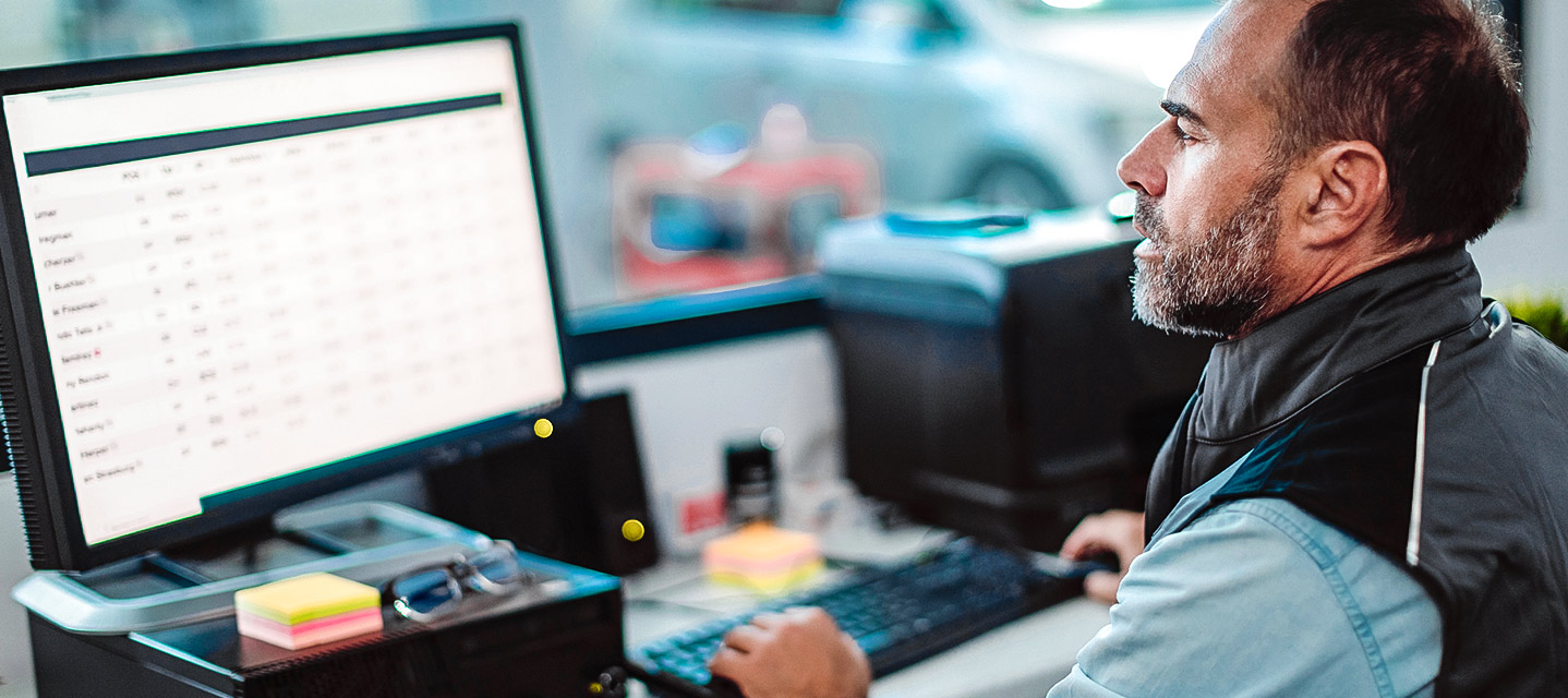 A fleet manager using a tablet to monitor a digital map with vehicle routes and real-time data overlays in a modern office.
