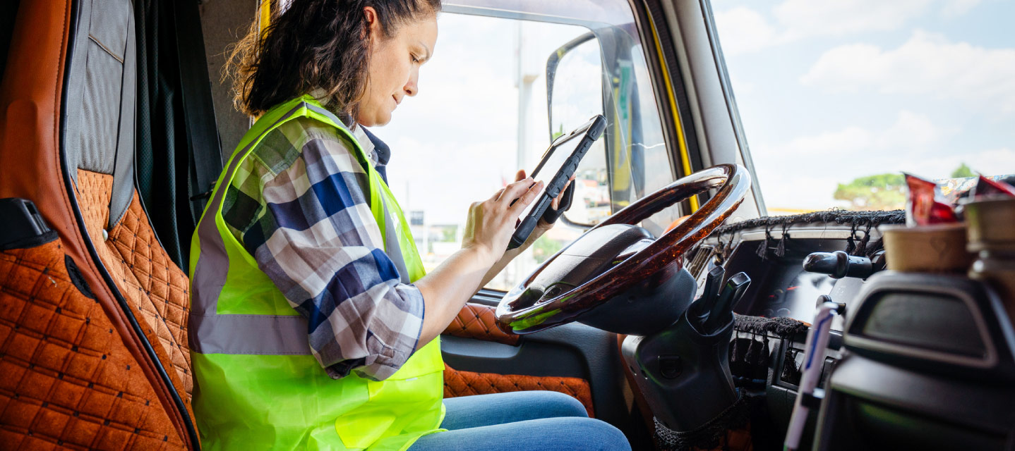 a woman in the drivers seat of a fleet vehicle looking at an ipad 