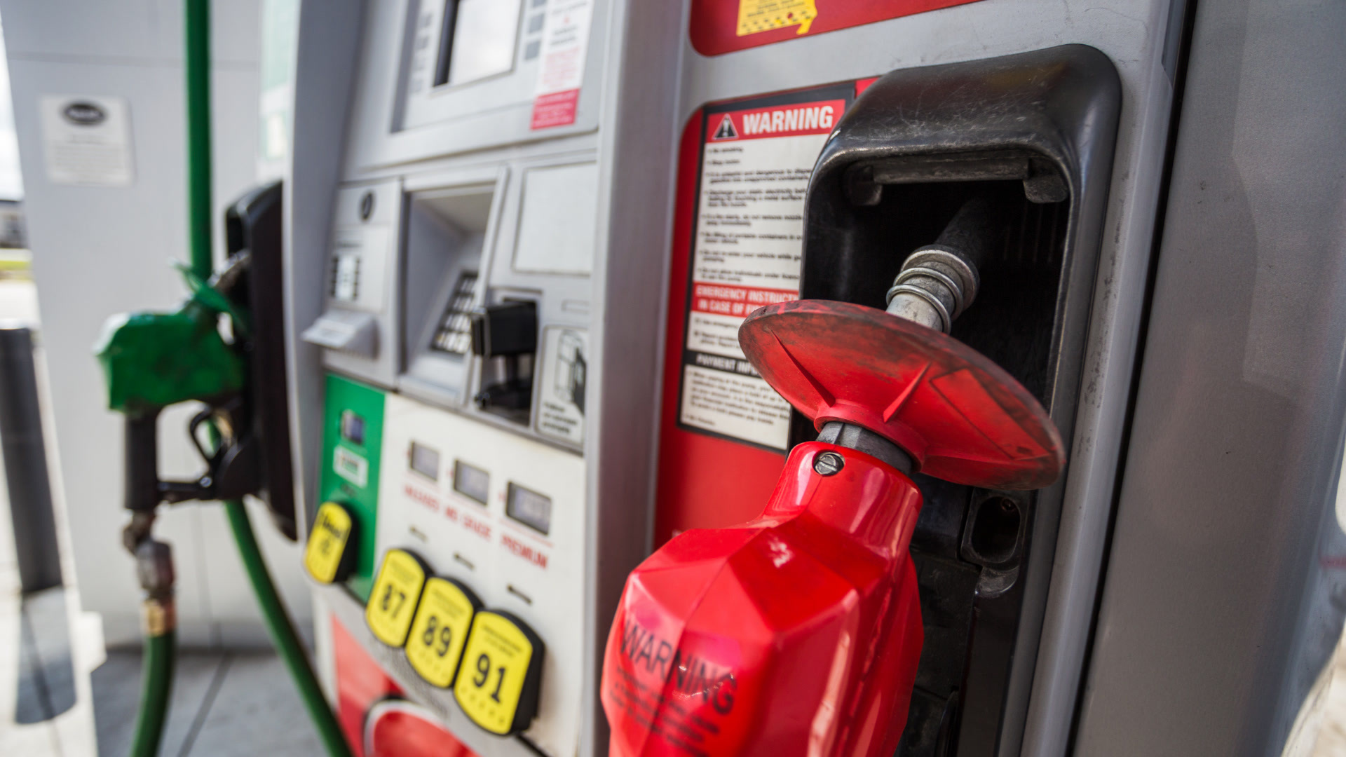 Close-up of a red fuel nozzle in a gas station pump where fleet fuel card fraud can occur