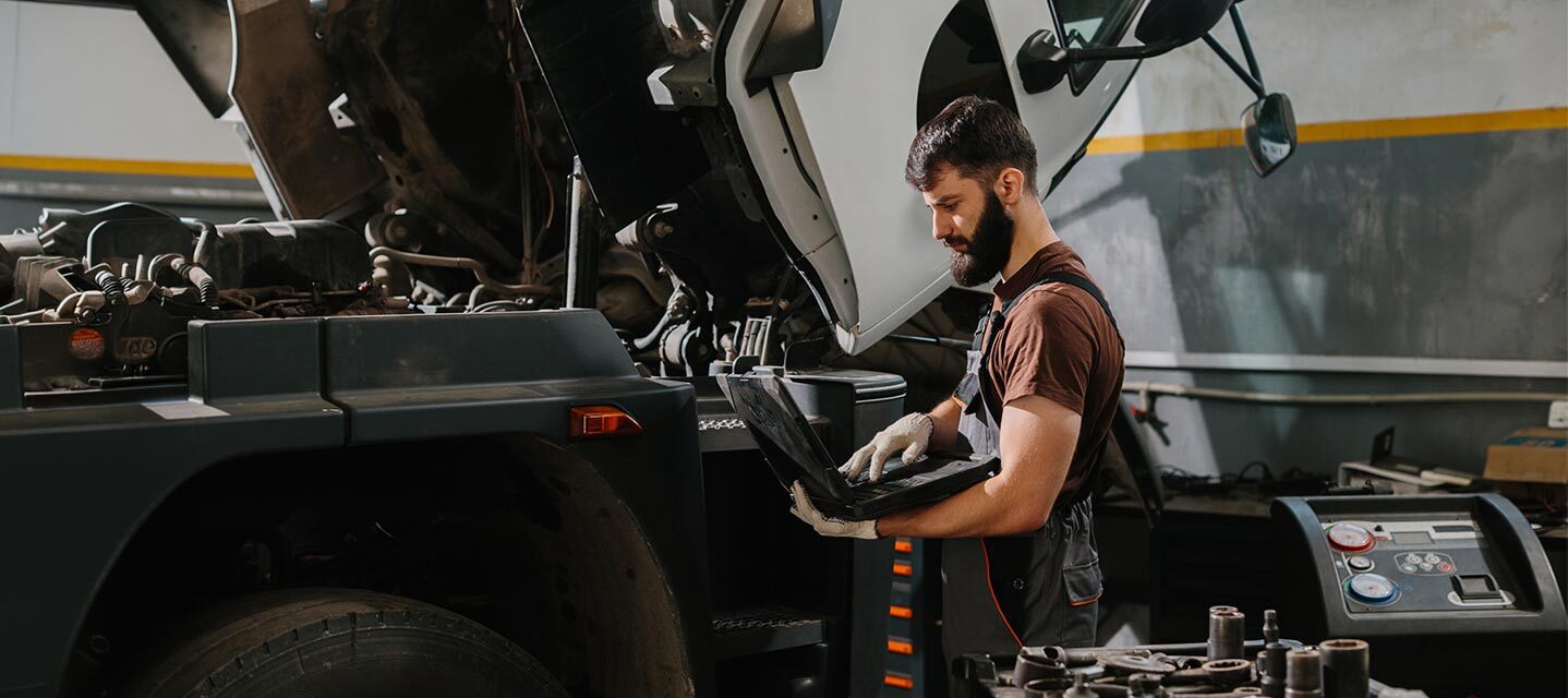 A man on a laptop in a fleet garage.