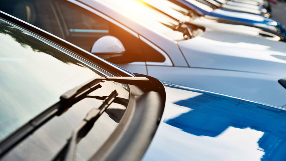 A photo of the sun reflecting off of a row of cars