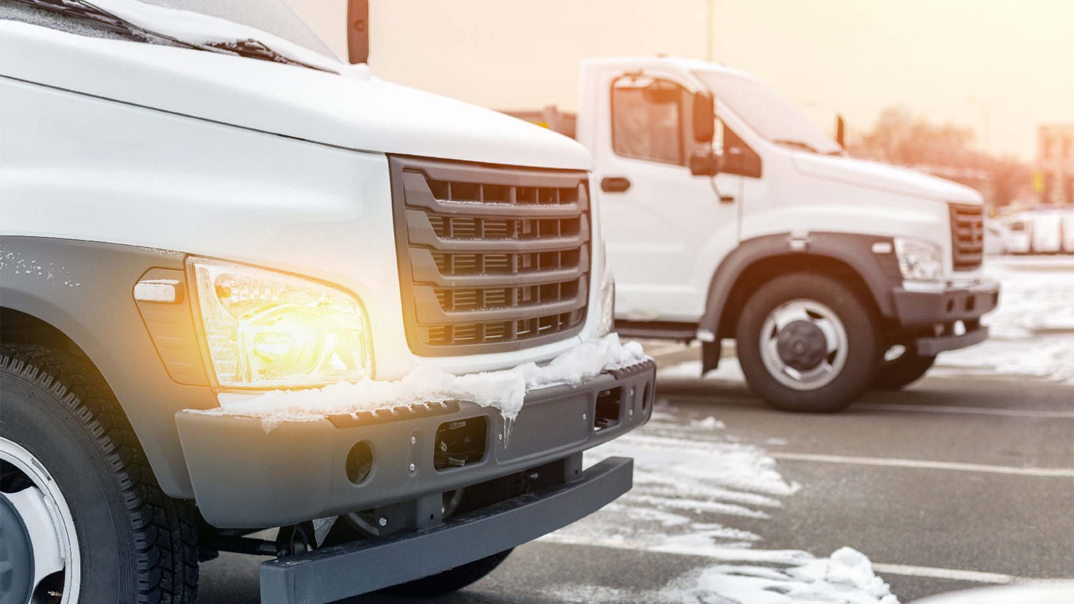 Two white trucks on snowy road