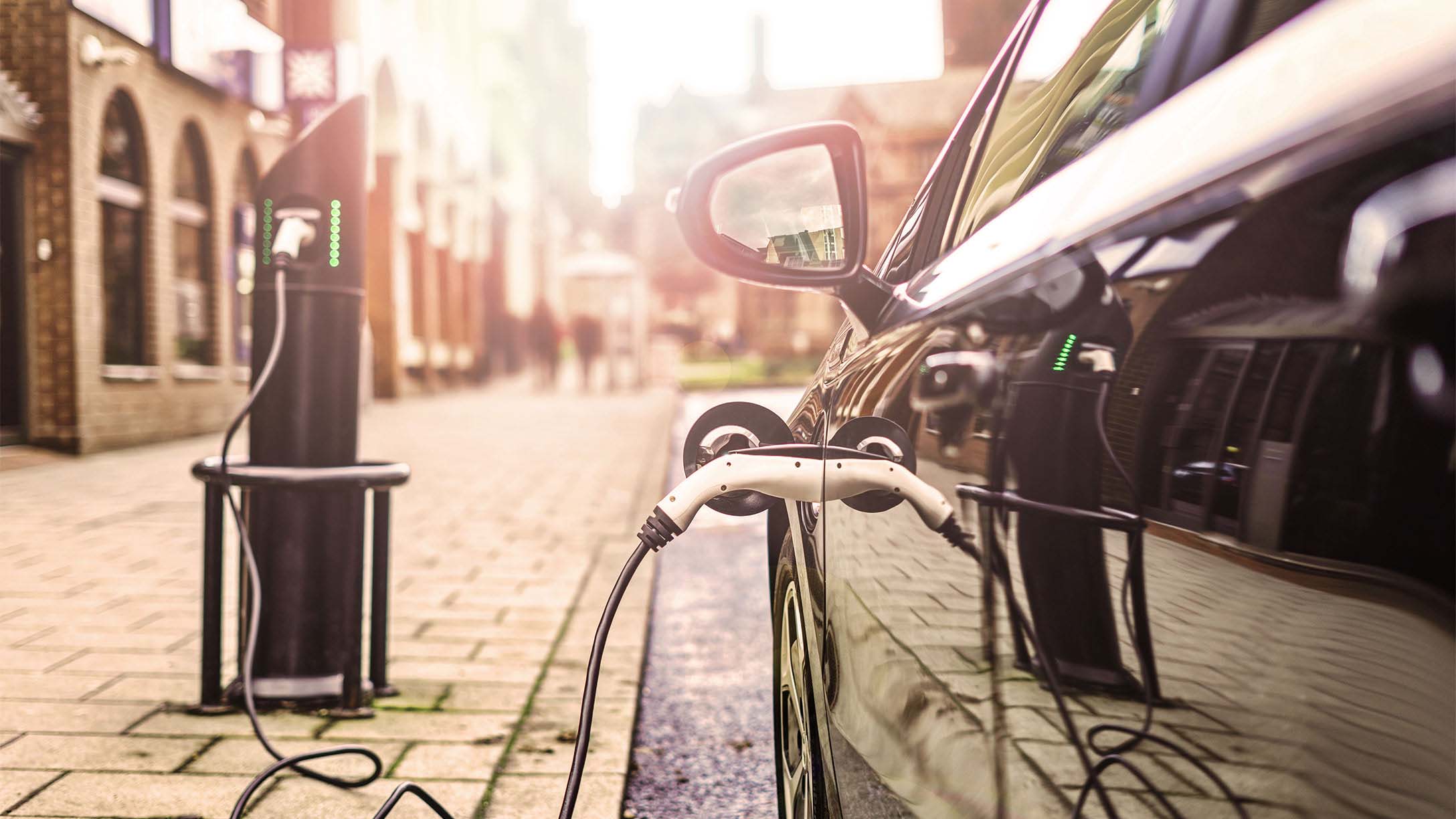 A black electric vehicle plugged into a charging station