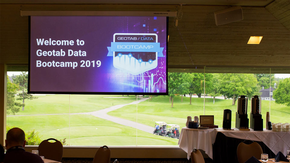 A screen in a conference room introducing Geotab Data Bootcamp 2019