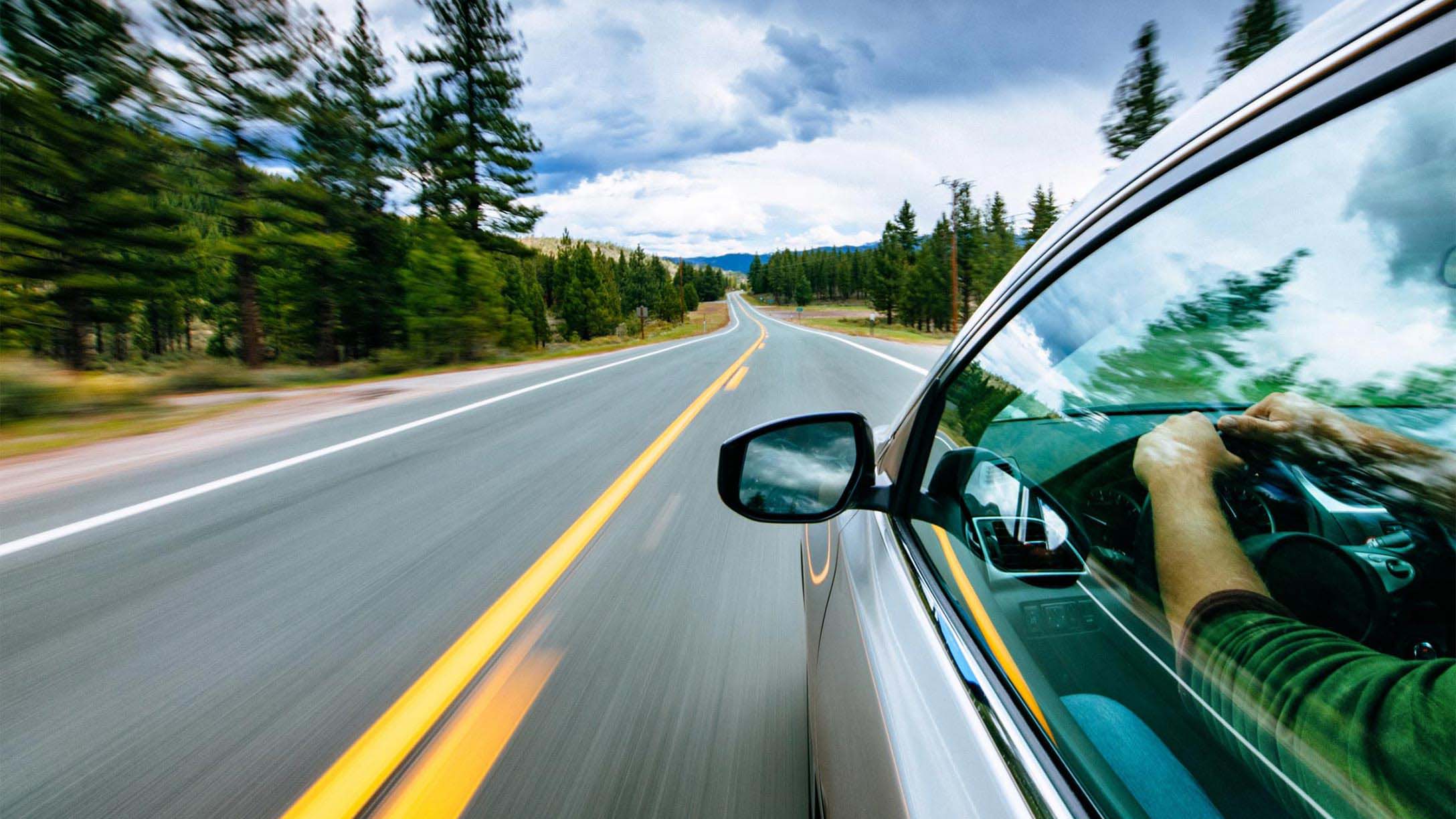 Side view of a person driving their car on an empty road