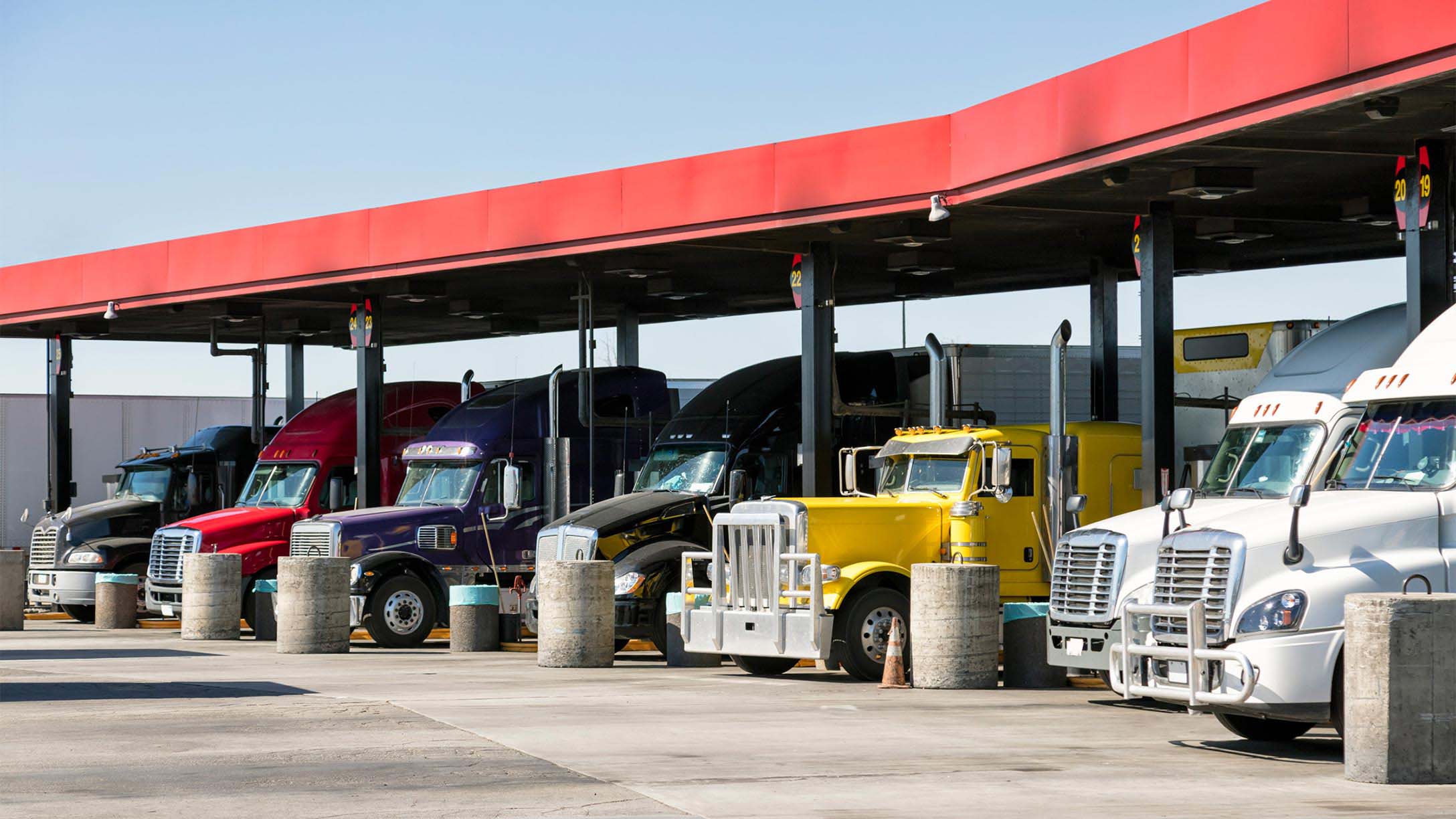 A row of semi trucks lined up at a fuel station