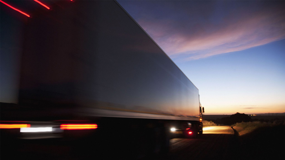 A semi truck driving at dusk