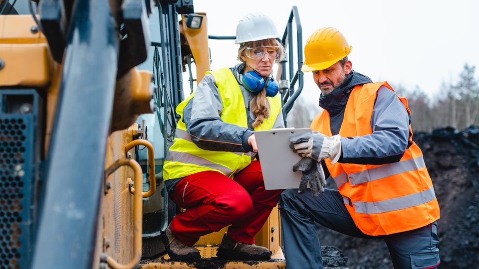 Two construction workers looking at a clipboard
