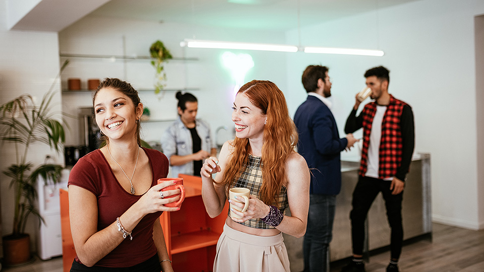 Two girls talking with more people in the background