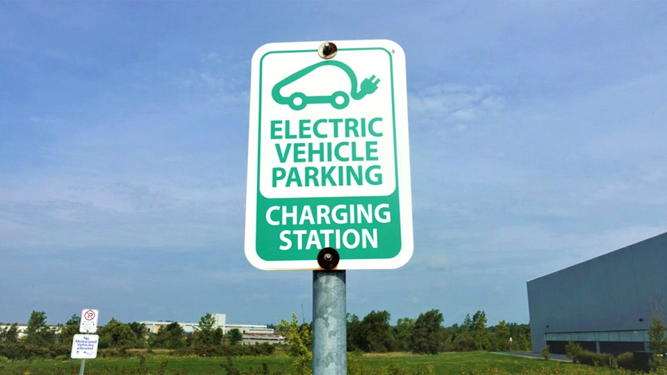 White and green sign that says "Electric Vehicle Parking Charing Station"