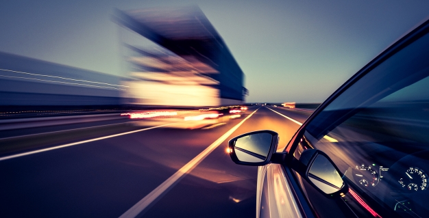 Side view of a car driving on a road with traffic passing by quickly