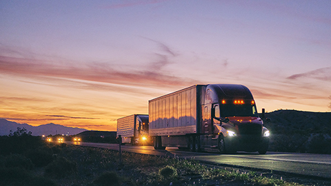 A lot of trucks with the evening sky in the background.  