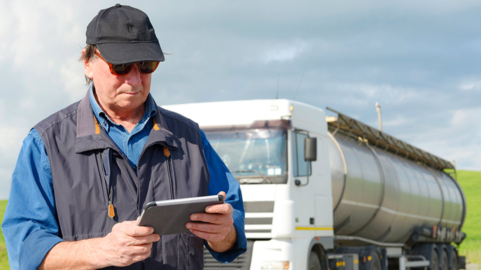 Man in a vest using an electronic logging device outside in front of a truck