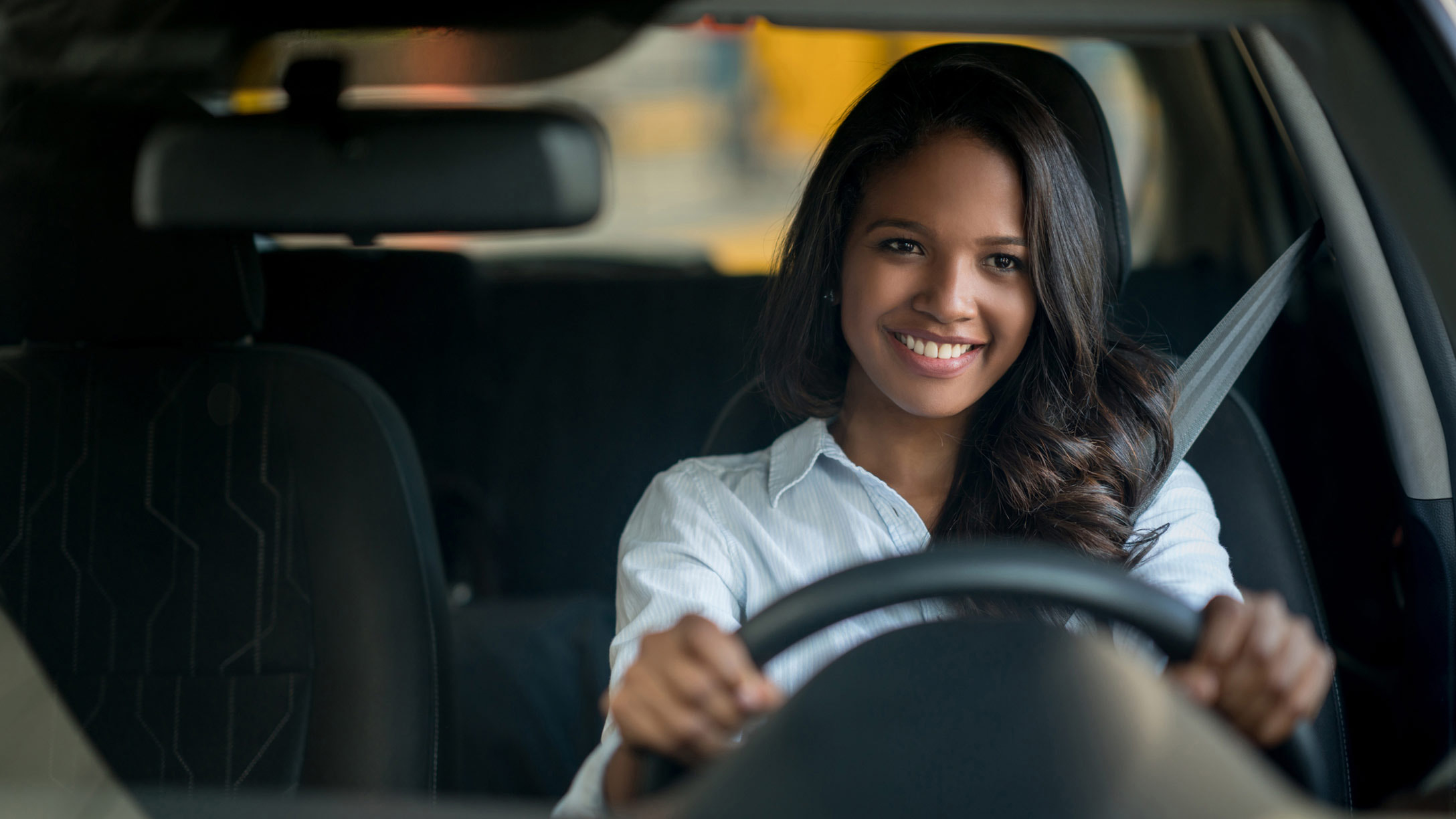 Young woman smiling while driving her car