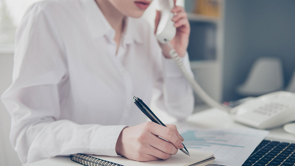 Person speaking on phone while writing something on paper