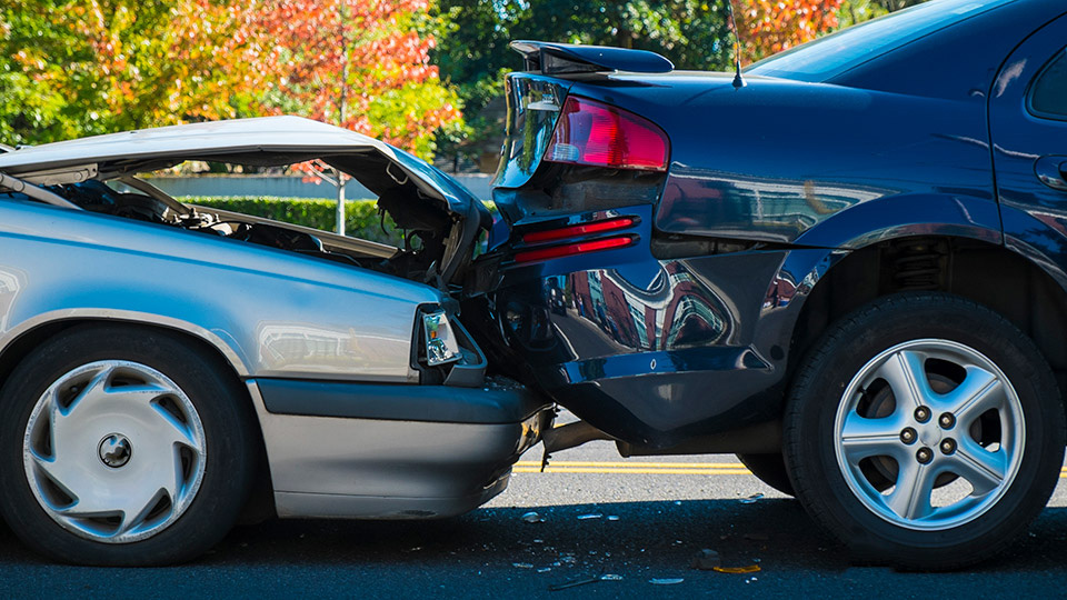 A silver vehicle crashing into the back of a black vehicle