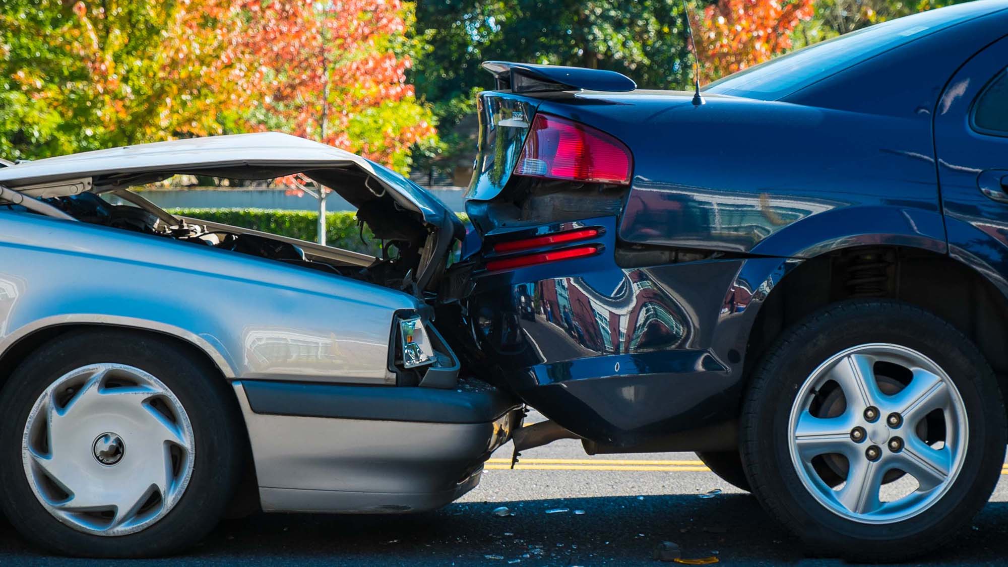 A silver vehicle crashing into the back of a black vehicle