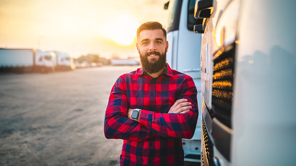 Man standing outside of their truck smiling with crossed arms