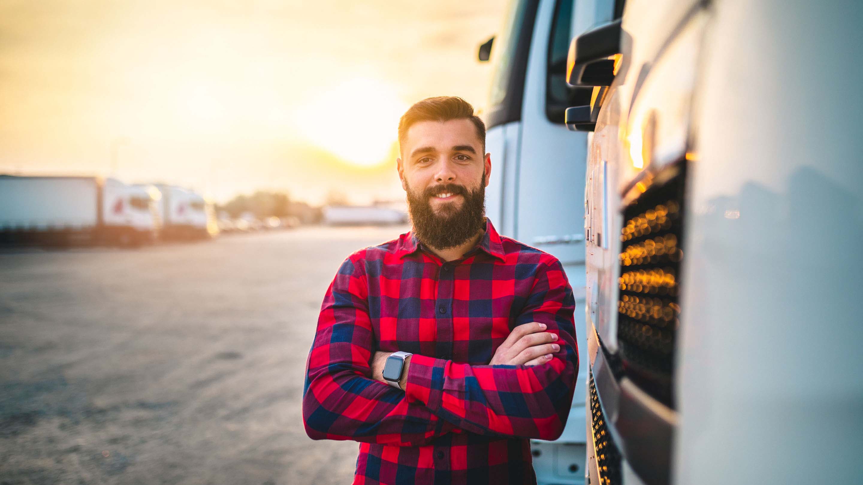 Man standing outside of their truck smiling with crossed arms