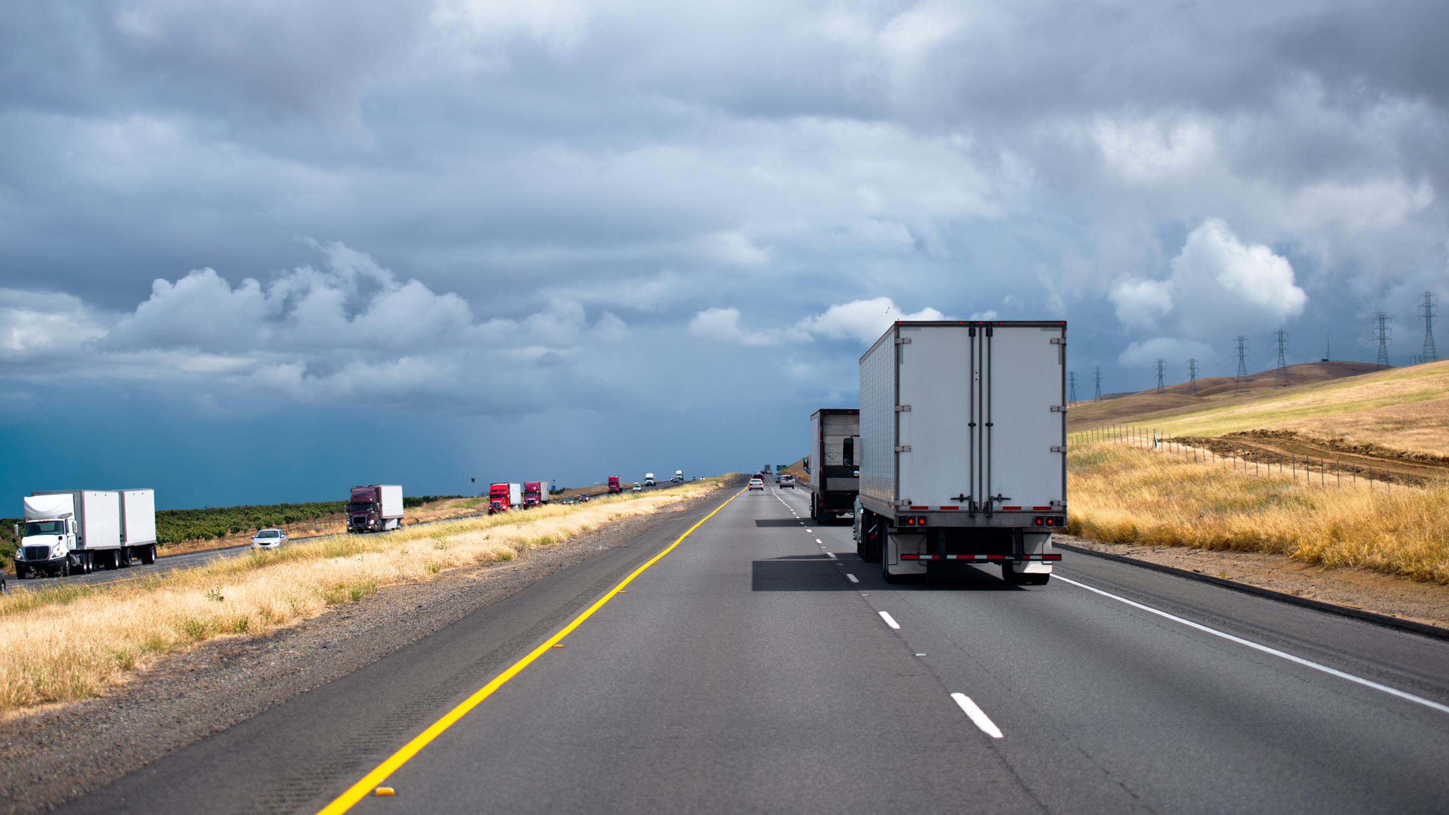 Vehicles driving on road with a cloudy sky 