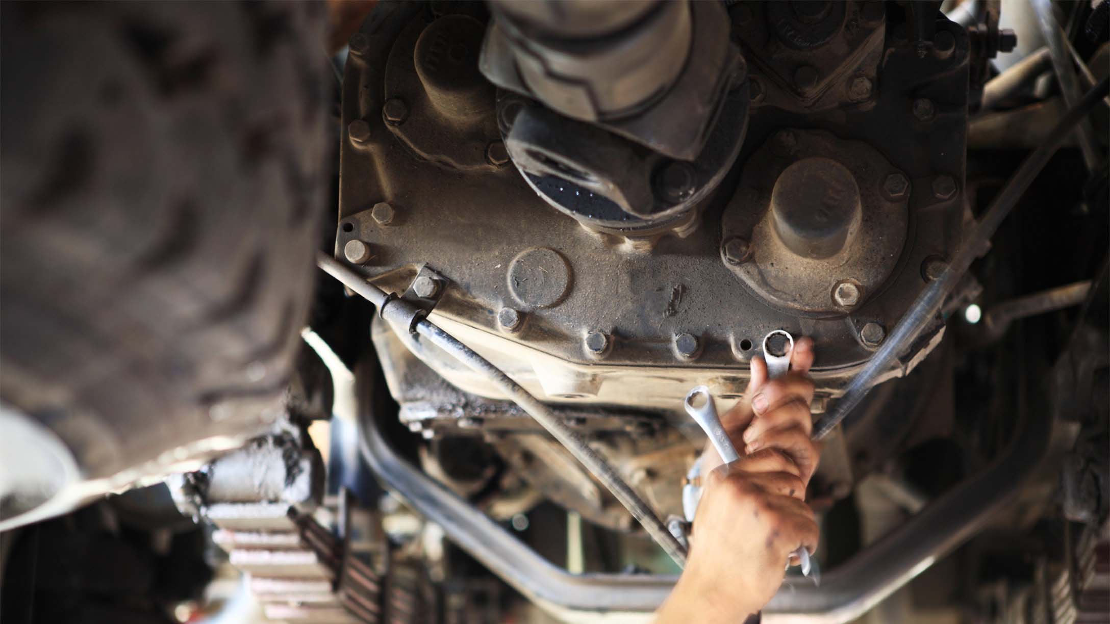 Mechanic working on the underside of a vehicle.