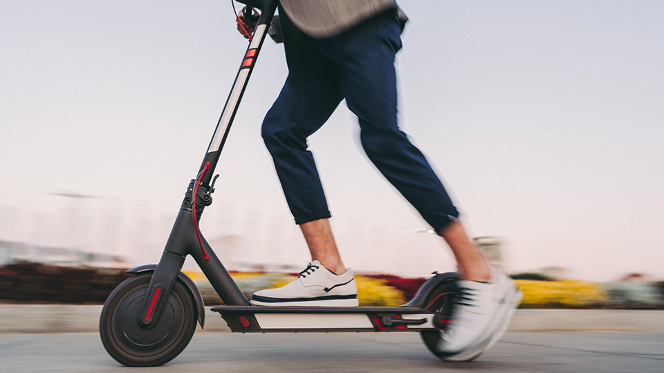 Immagine di un monopattino in corsa guidato dalle gambe di un uomo