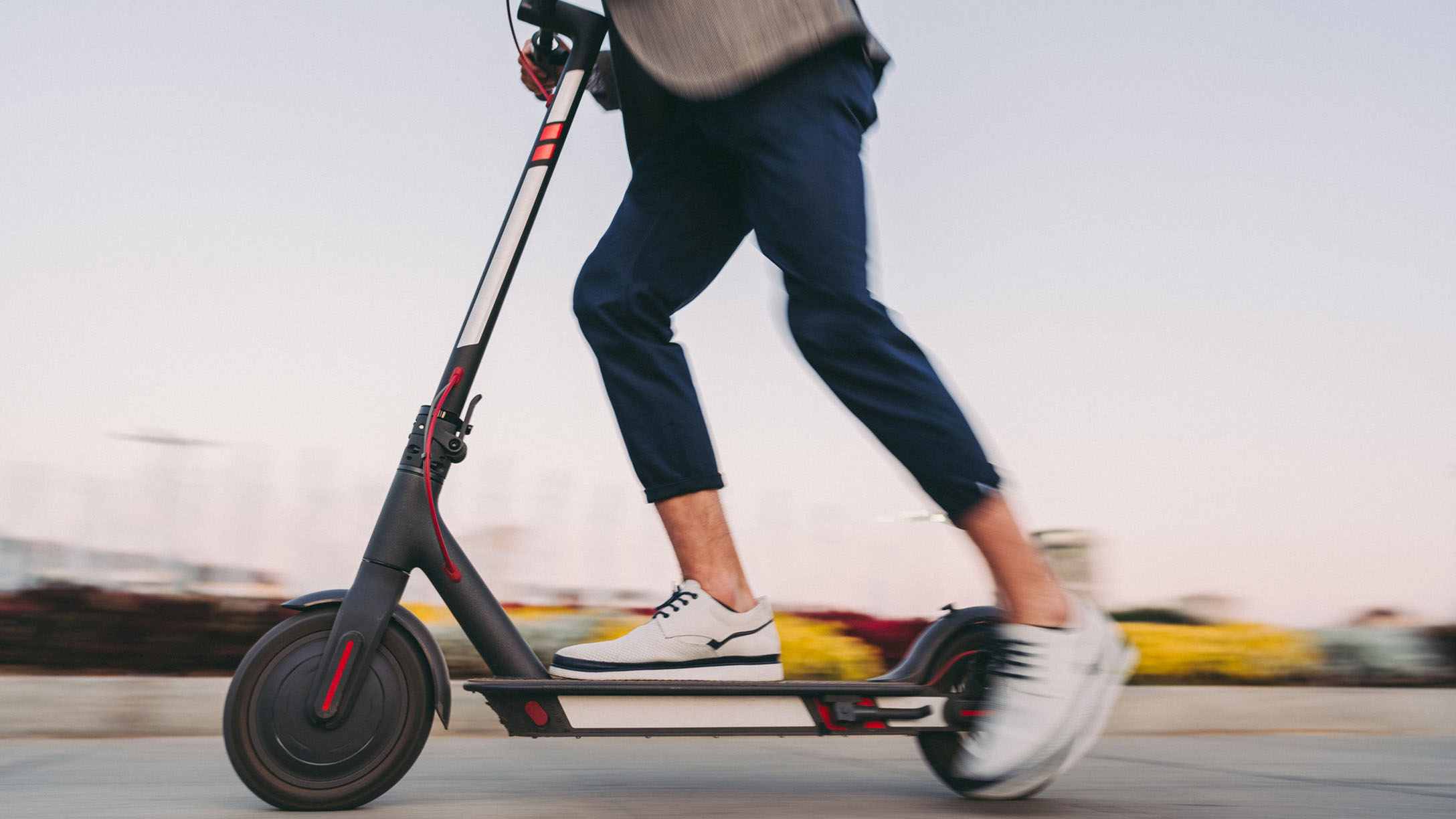 Immagine di un monopattino in corsa guidato dalle gambe di un uomo