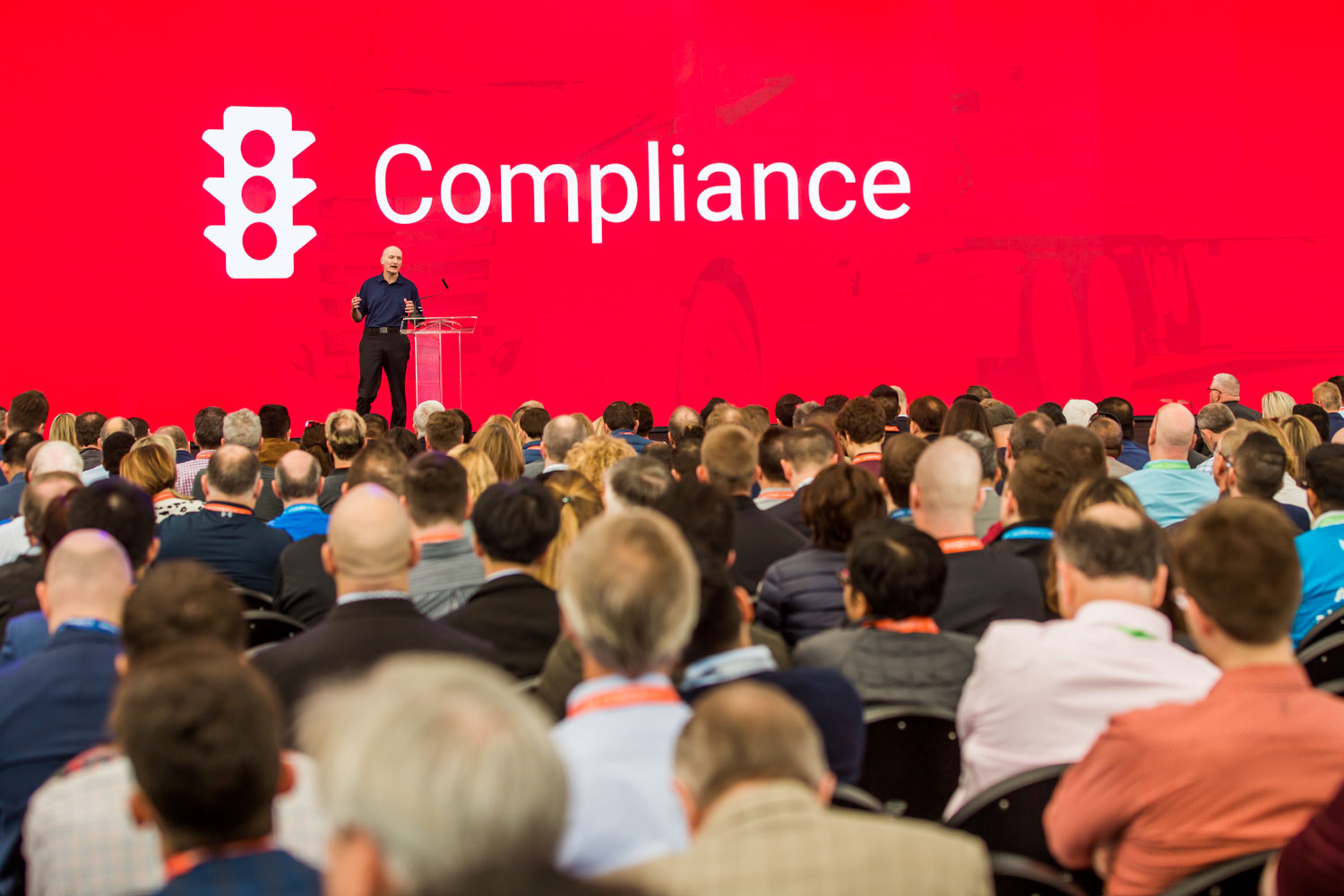 A man on stage standing in front of a red background