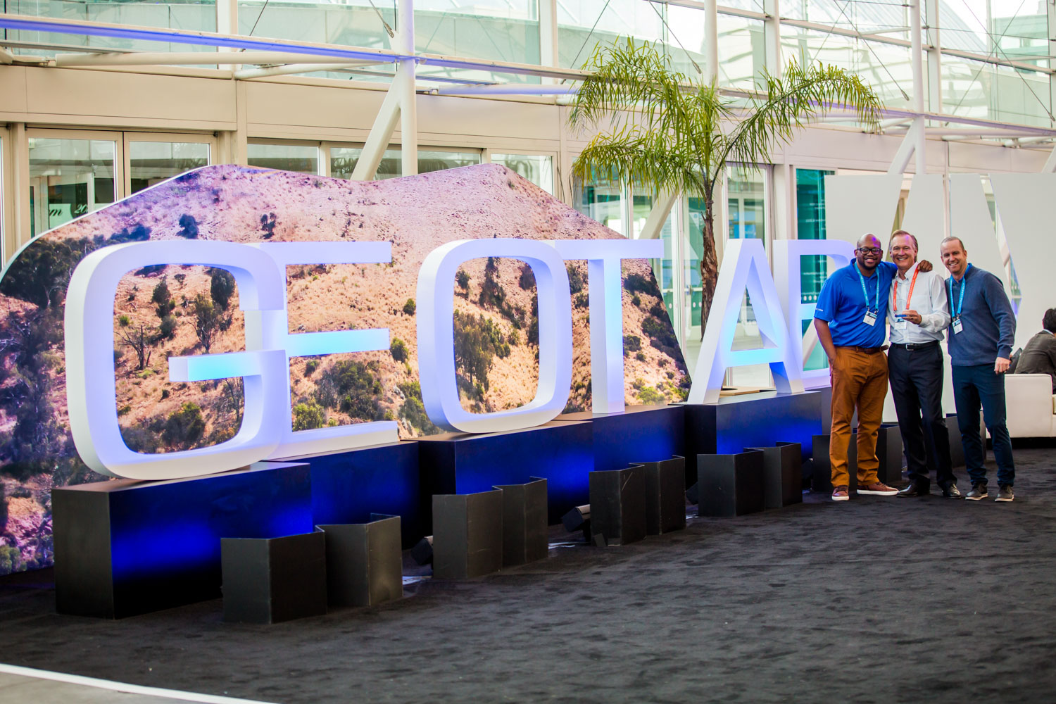three men posing in front of a Geotab sign