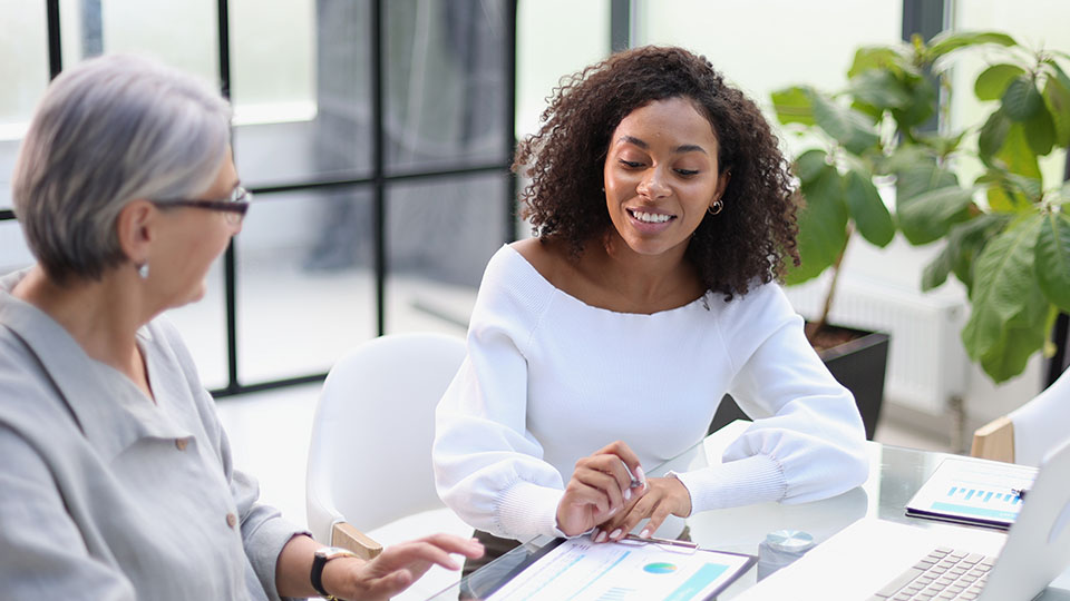 Two women in a business meeting sitting in front of charts and a laptop