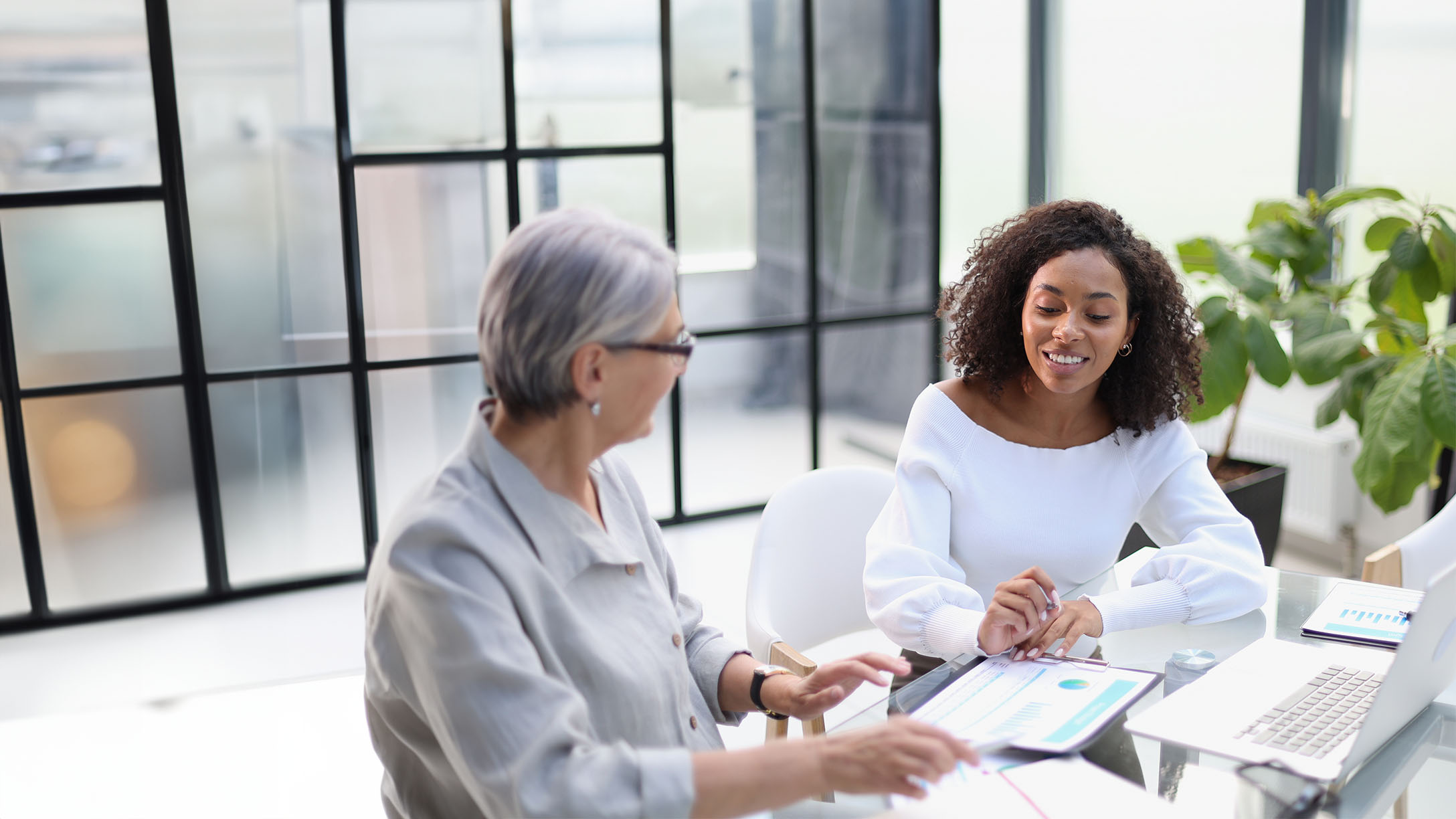 Two women in a business meeting sitting in front of charts and a laptop